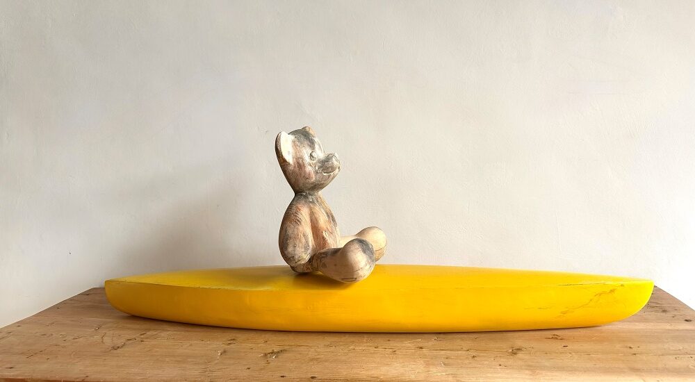 Teddy auf Kajak - Eine Holzskulptur aus Lindenholz/Walnussholz von Künstler Klaus Metz.