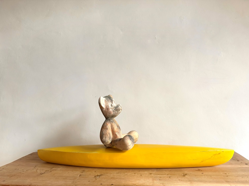 Teddy auf Kajak - Eine Holzskulptur aus Lindenholz/Walnussholz von Künstler Klaus Metz.